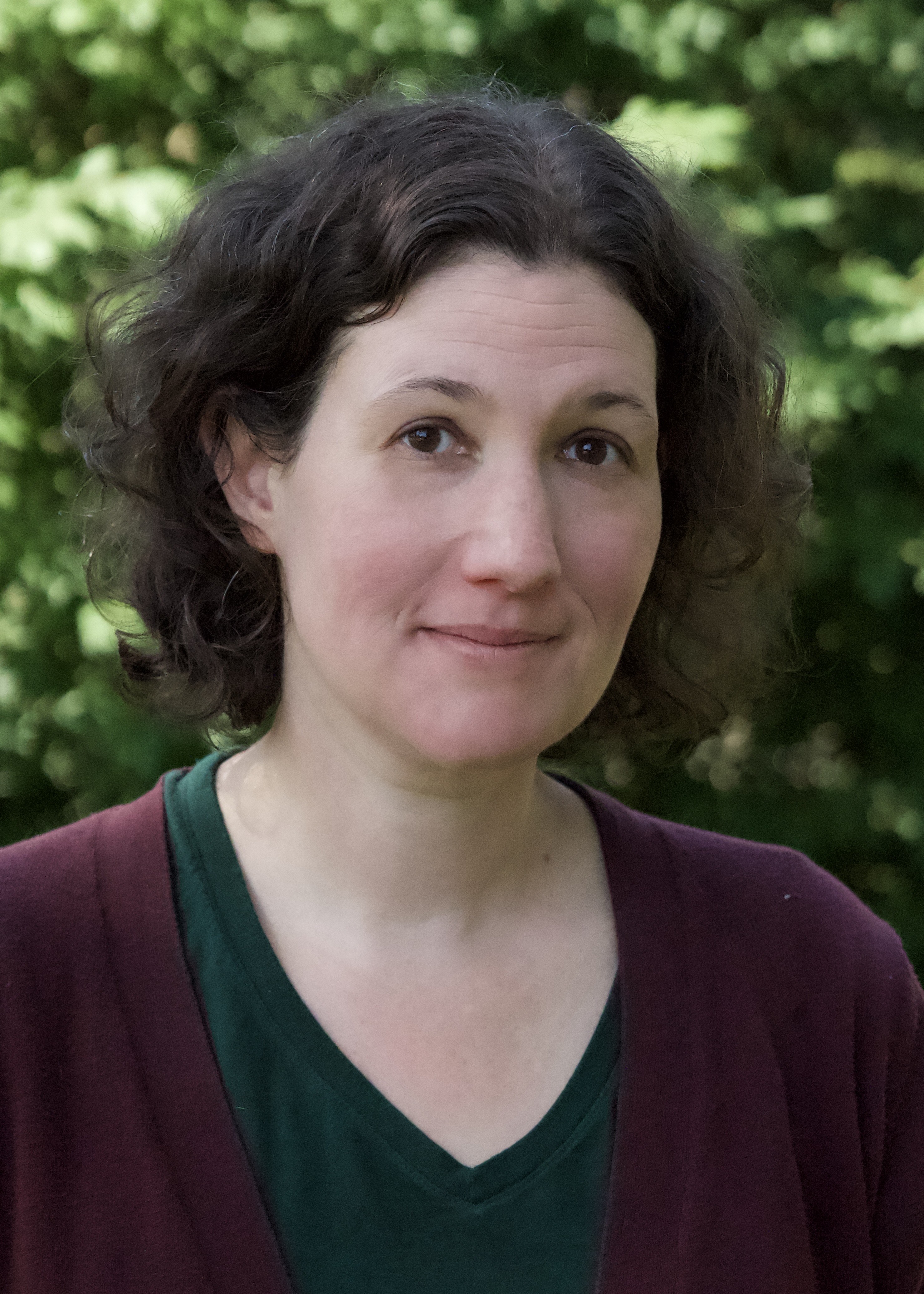 A headshot of Debby Hoskin in a green shirt and maroon shawl.